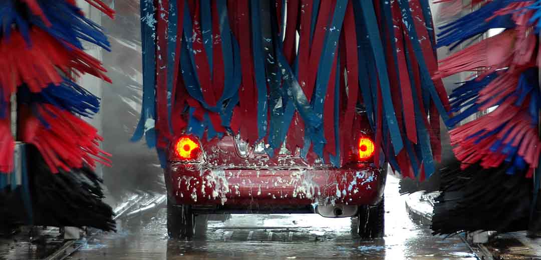 Commercial vehicle wash system with car moving through automated cleaning equipment
