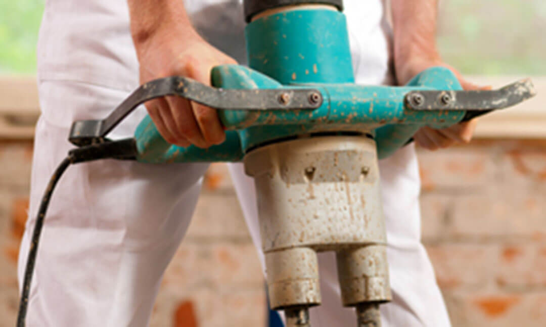 Worker using a concrete vibrator to consolidate poured concrete