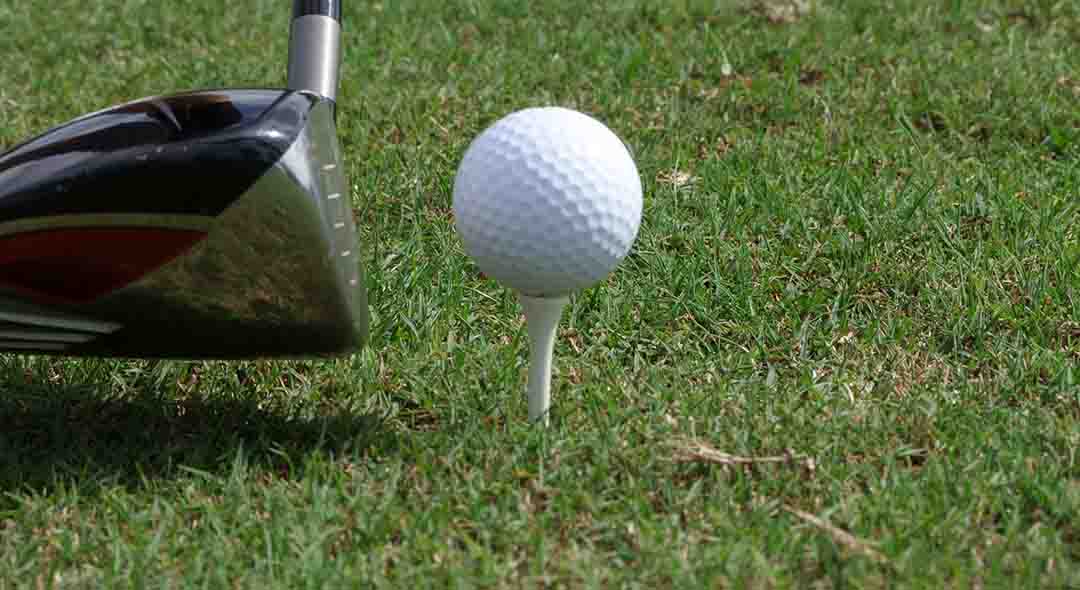 Close-up of a golf ball on a tee being hit with a golf club